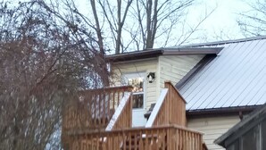 A wooden deck with stairs leading to a covered area, surrounded by snow.