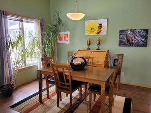 A dining area with a wooden table and chairs, a potted plant, and artwork on the walls.