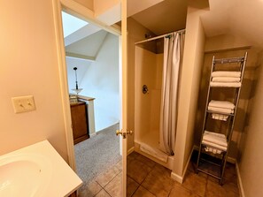 Une salle de bain avec une douche, un porte-serviettes et un lavabo.
