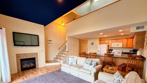 A living room with a fireplace, a sofa set, a dining area, and a kitchen. - Gorgeous Townhouse & Boathouse in Cozy Carnegie Bay (Alexandria Bay)