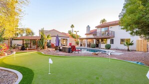 A residential property with a backyard featuring a swimming pool, a patio with outdoor furniture, and a well-maintained lawn. - Family-Friendly Retreat, Heated Pool, Putting Green (Scottsdale)