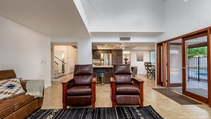 A spacious living area with a sofa, two leather chairs, a coffee table, and a kitchen in the background. - Family-Friendly Retreat, Heated Pool, Putting Green (Scottsdale)