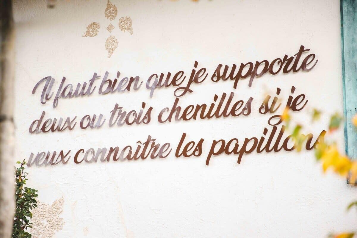 A wall with a decorative metal sign featuring a French quote.