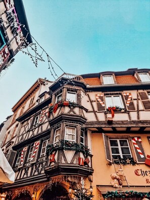 Un edificio tradicional de entramado de madera con varias ventanas, algunas decoradas con motivos de bastones de caramelo, y un letrero que indica un restaurante.