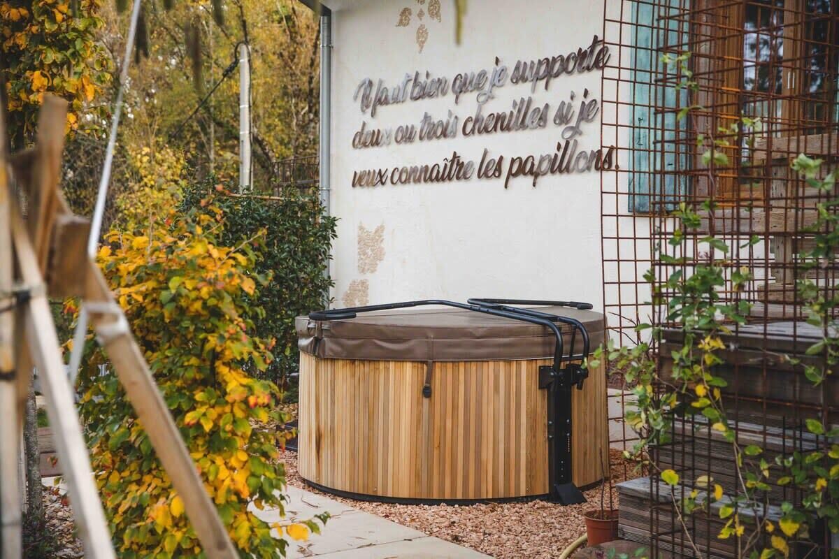 Ein Whirlpool in einem Garten mit einer Wand, die französische Schriftzeichen enthält.