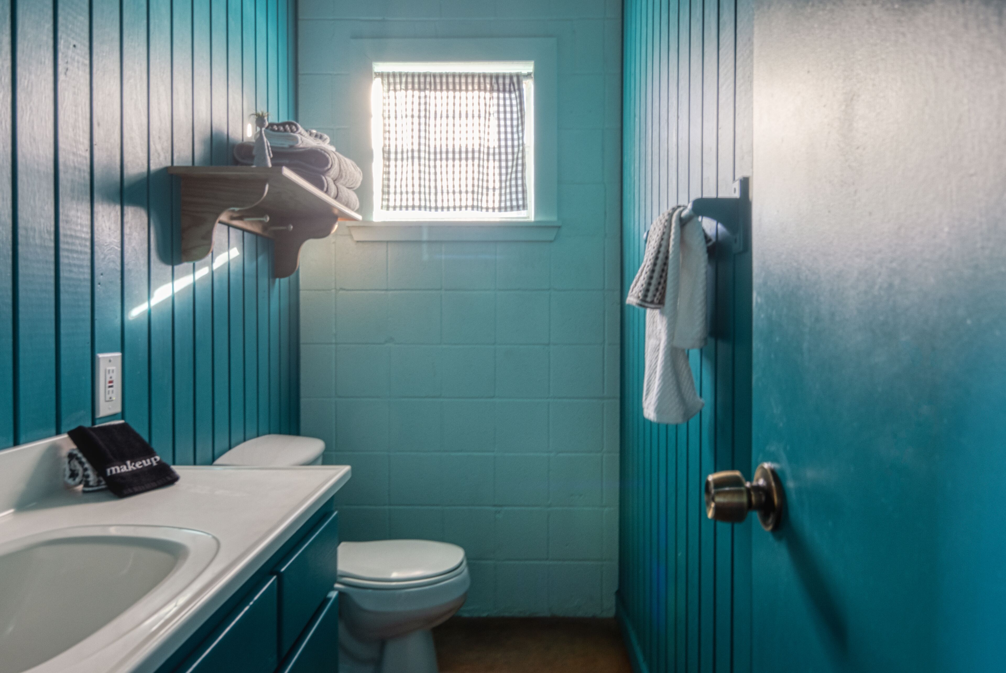 Une petite salle de bain avec des toilettes, un lavabo et une fenêtre.