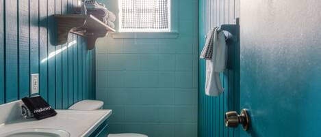 Une petite salle de bain avec des toilettes, un lavabo et une fenêtre.
