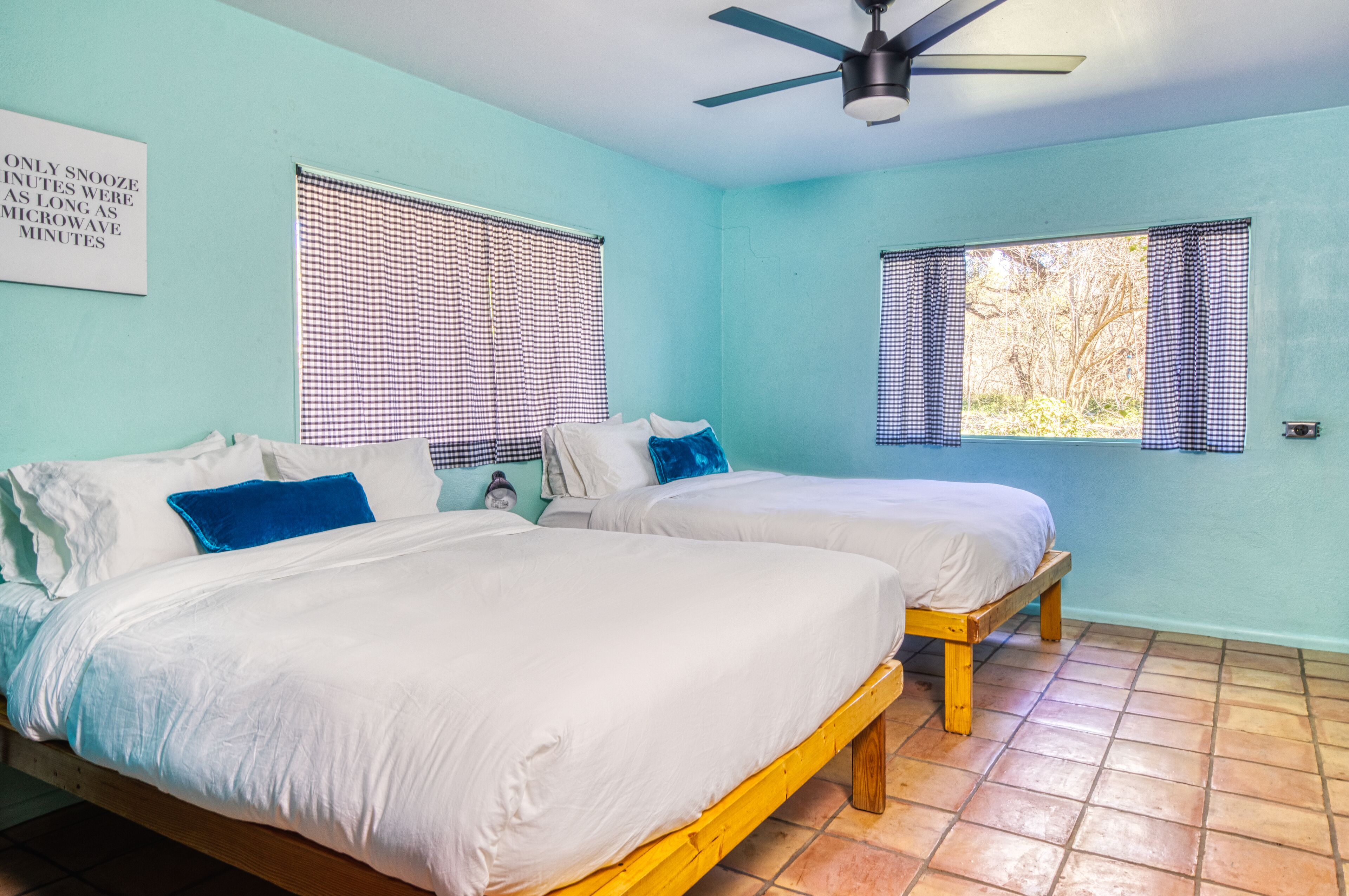 A room with two beds, a ceiling fan, and a sign on the wall.