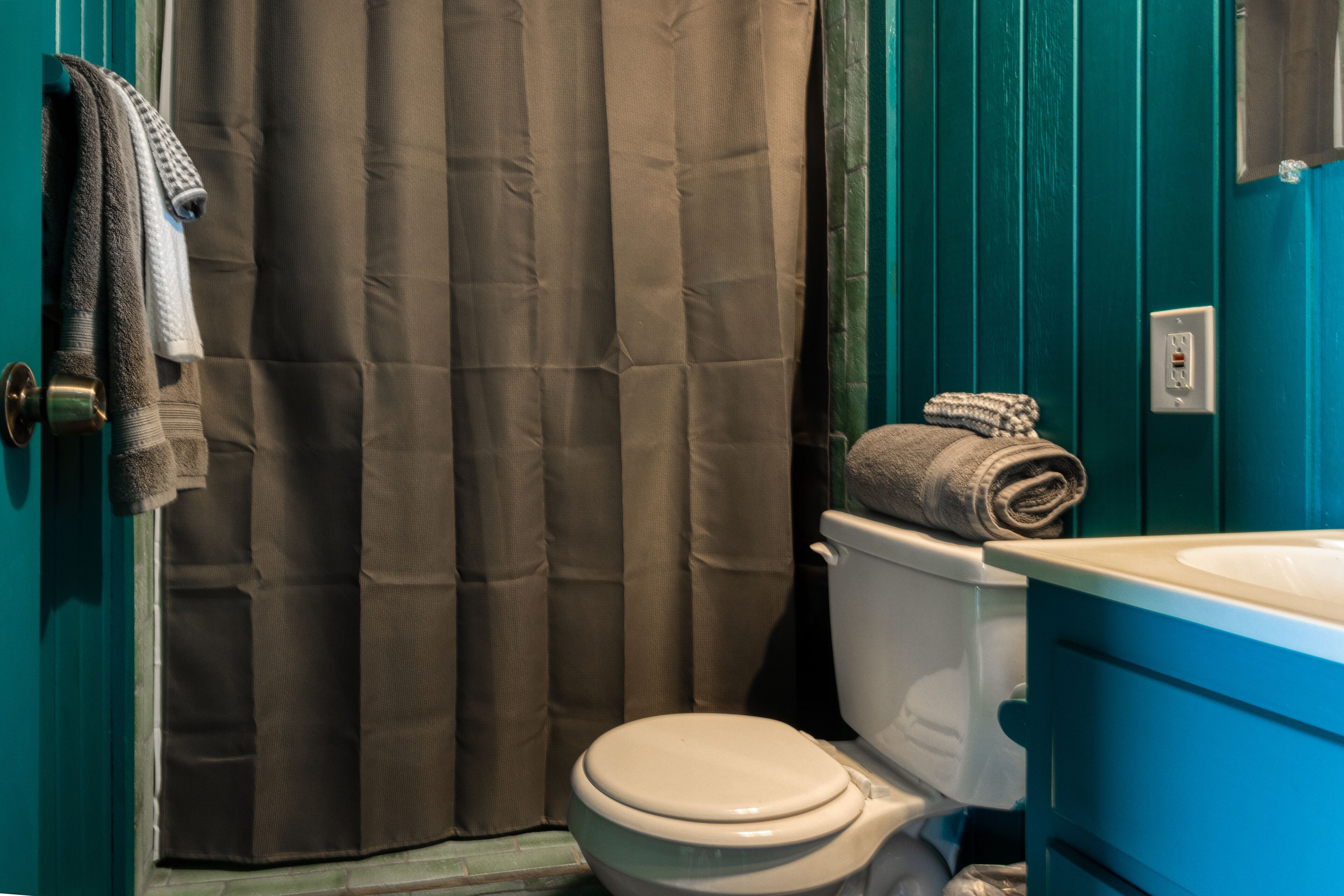 A bathroom with a toilet, a blue sink, and a brown shower curtain.