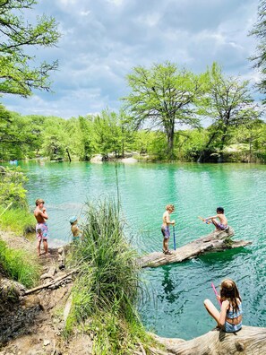 A natural outdoor setting with a body of water, trees, and people engaging in water activities.