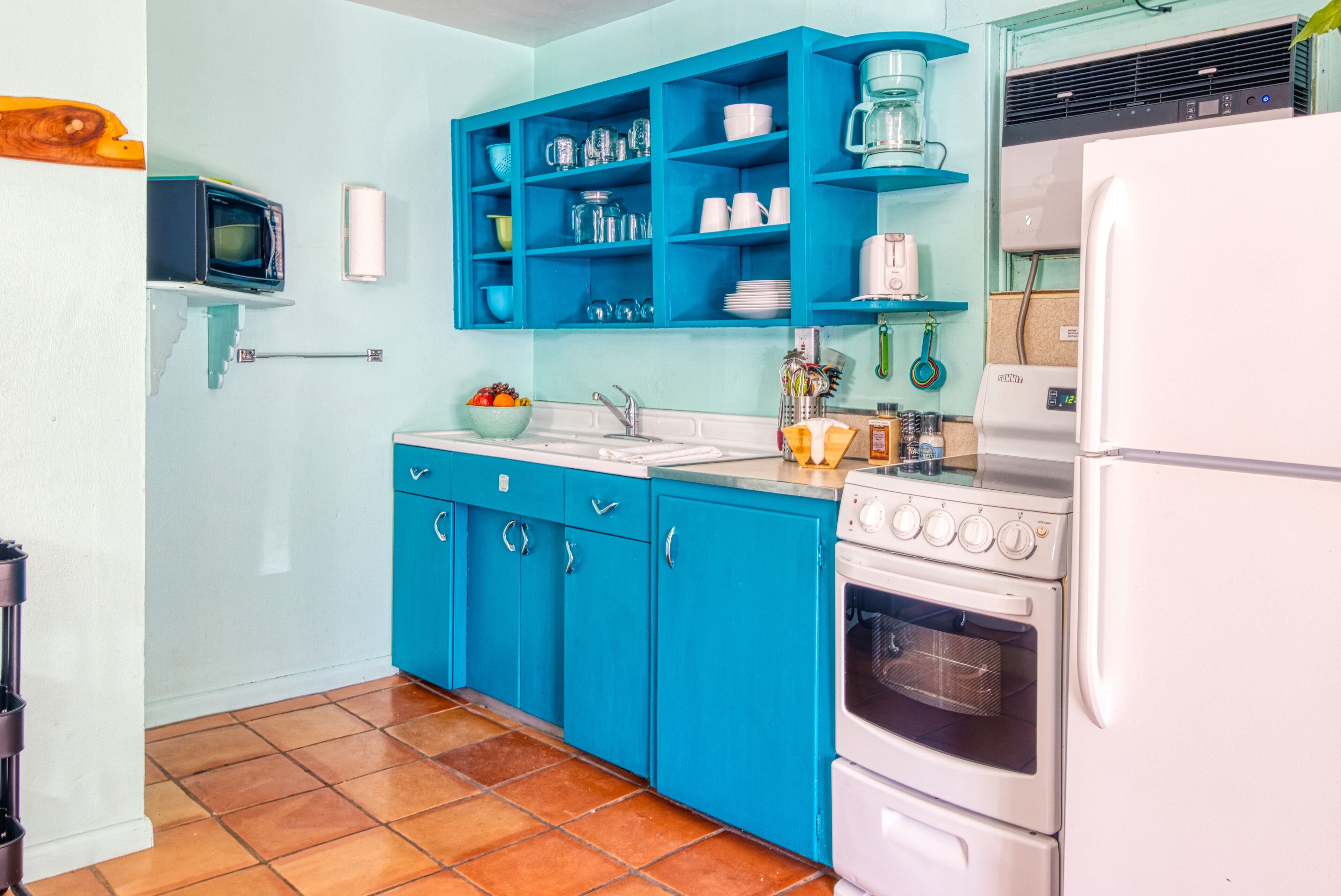 Une cuisine avec des meubles de couleur turquoise, un réfrigérateur blanc et une cuisinière.