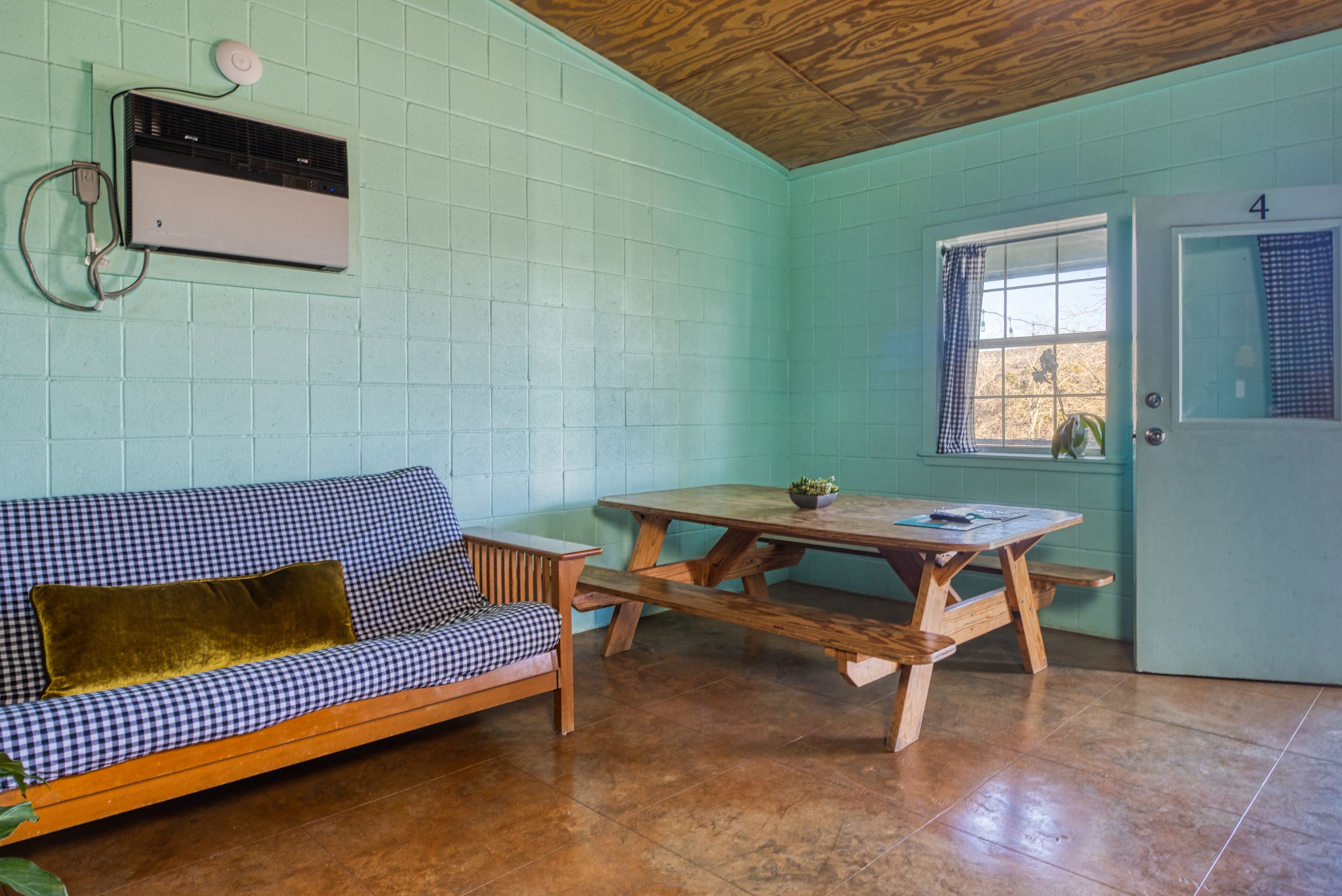 Una habitación con un sofá a cuadros, una mesa de madera y una puerta marcada con el número 4.