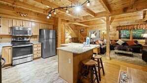 Ein Holzblockhaus-Innenraum mit Küche, Wohnbereich und einer Treppe.