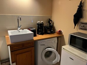 Eine kompakte Küche mit Spüle, Toaster, Kaffeemaschine und Waschmaschine.