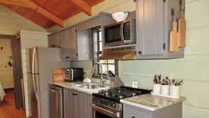 A compact kitchen with a stainless steel refrigerator, a microwave, a stove, and a sink. - Fabulous Cabin Near Falls, Hiking, and Fly-Fishing (Brevard)