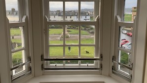 A bay window with multiple panes, offering views of a grassy area and parked cars. - Ayr Loft Apartment With Fabulous Views (Ayr)