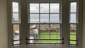 A bay window with multiple panes, overlooking a residential area with houses and a green lawn. - Ayr Loft Apartment With Fabulous Views (Ayr)