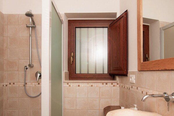 Une salle de bain équipée d’une douche, d’un lavabo, d’un miroir et d’une fenêtre avec un cadre en bois.
