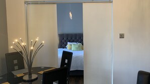 Ein modernes Zimmer mit einem Bett, einem Esstisch mit Stühlen und einer dekorativen Leuchte.