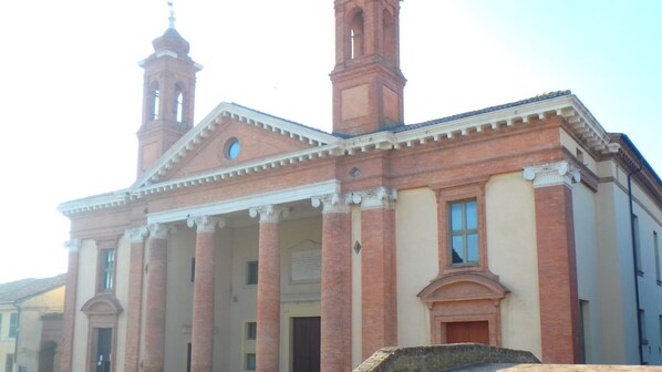 A historic building with a central entrance flanked by columns, a bell tower, and a clock.