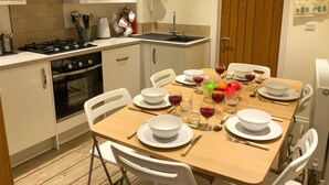 A modern kitchen with white cabinets, a gas stove, and a dining table set for six with white plates and bowls. - 3 bedroom accommodation in Cowes (Cowes)