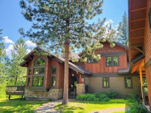 A two-story lodge with a stone foundation, large windows, and a prominent tree in the front yard. - Aspen Grove - 4-Bedroom Home in Mazama (Winthrop)