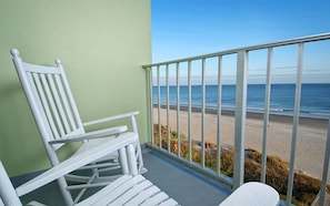Enjoy the ocean view from this balcony with a rocking chair and table.