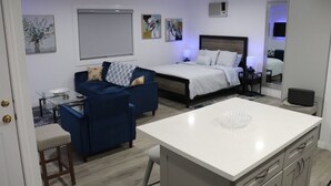 A modern hotel room with a bed, a desk, a blue sofa, and artwork on the walls.