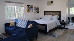 A modern bedroom with a large bed, a blue sofa, and two abstract paintings on the wall.