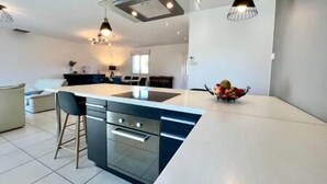 Una cocina moderna con una isla central, taburetes de bar e iluminación colgante.