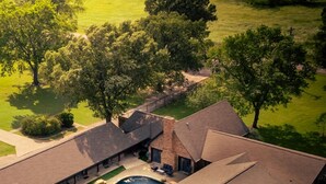 Una casa grande con piscina, varios garajes y un césped bien cuidado.
