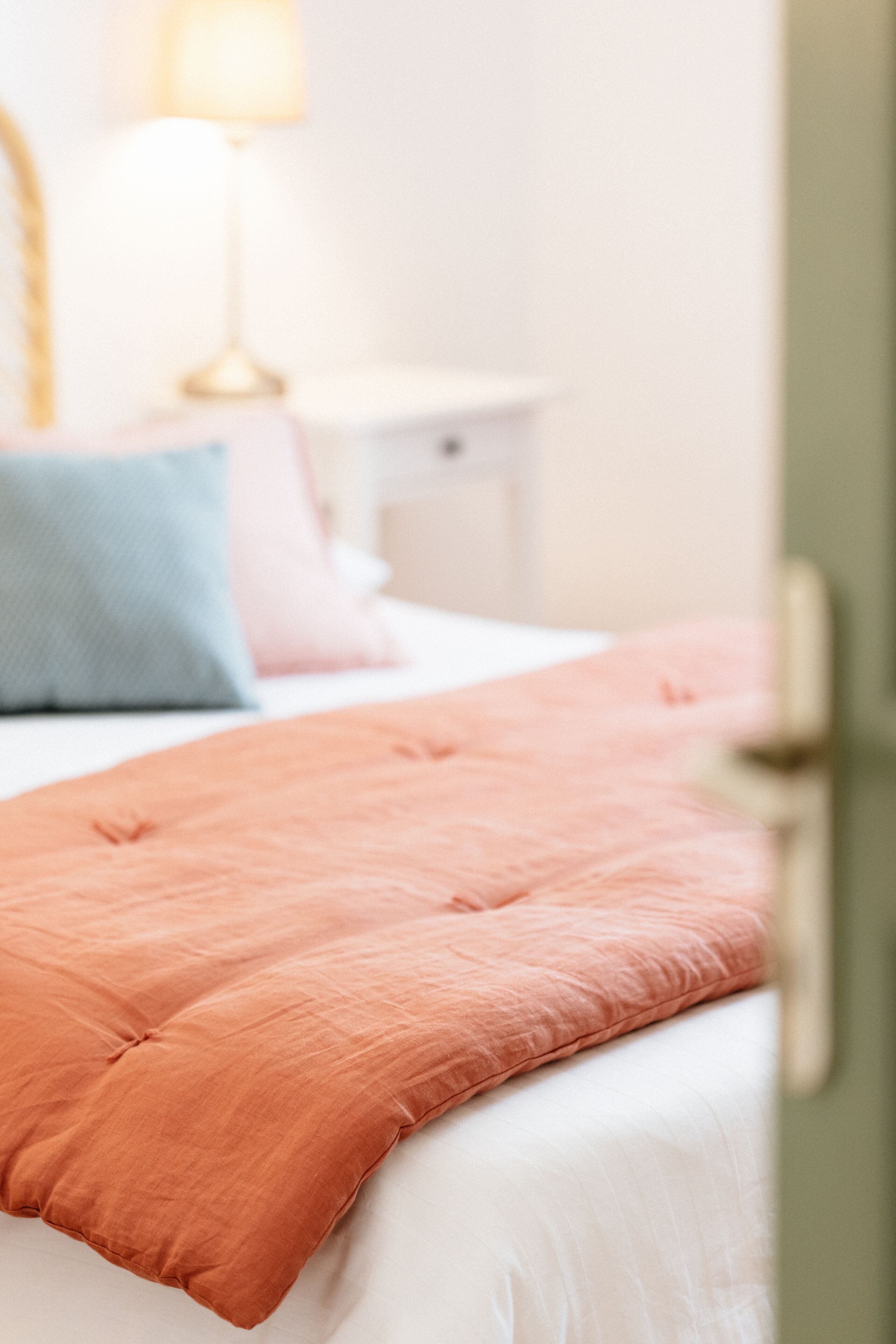 A neatly made bed with a pink pillow and a blue pillow.