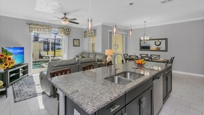 A modern kitchen with granite countertops, a central island, and a dining area with chairs. - Water Slide Resort Close 2 Disney! VALUE Priced! 4886 (Kissimmee)