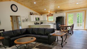 A spacious living area with a sectional sofa, a coffee table, and a dining table with chairs.