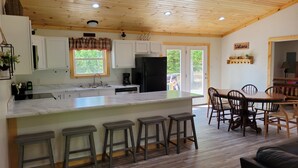 A modern kitchen with a large island, bar stools, and a dining area with a wooden table and chairs.