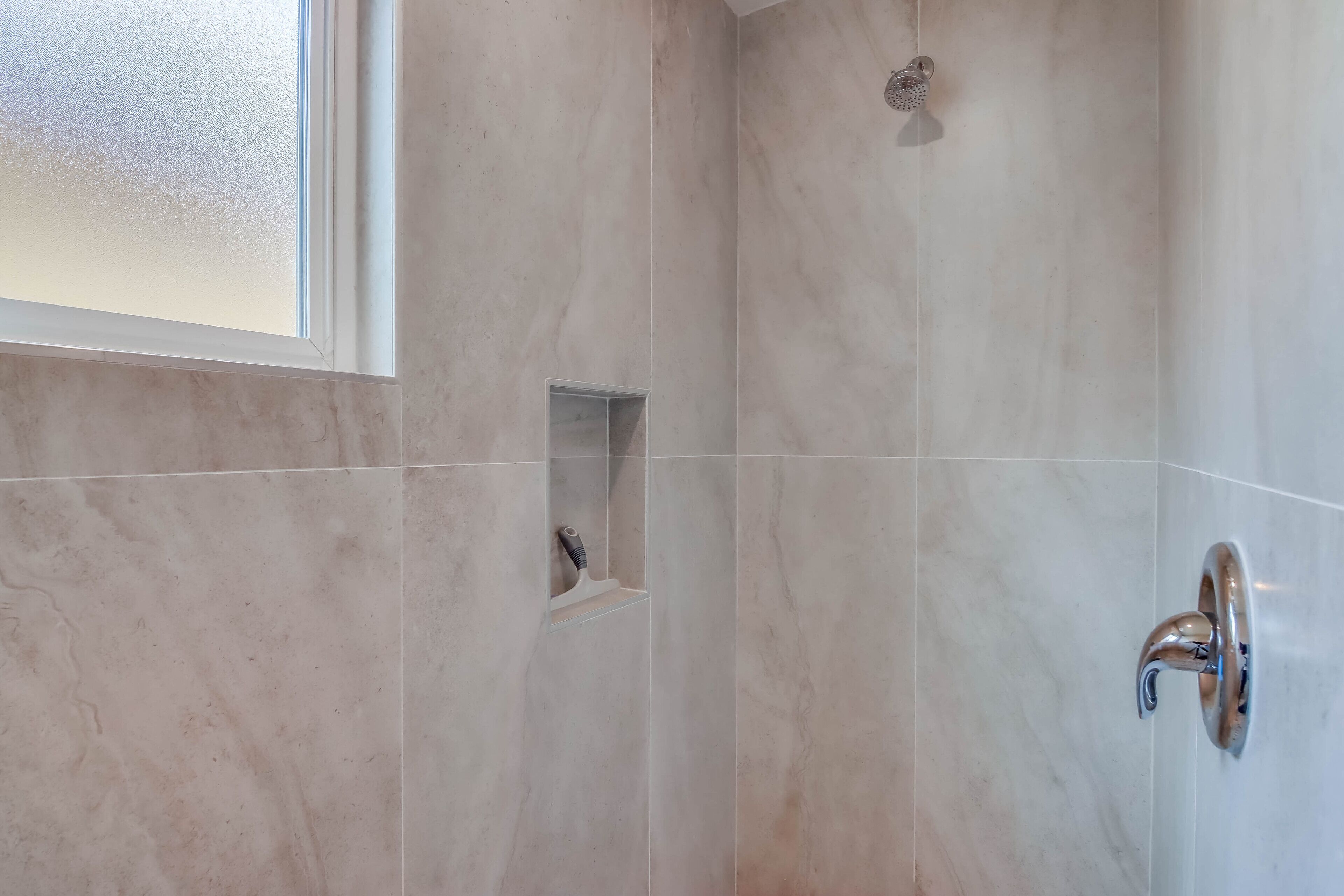 Une salle de bain avec une douche, une petite étagère avec une brosse à cheveux et un porte-serviettes.