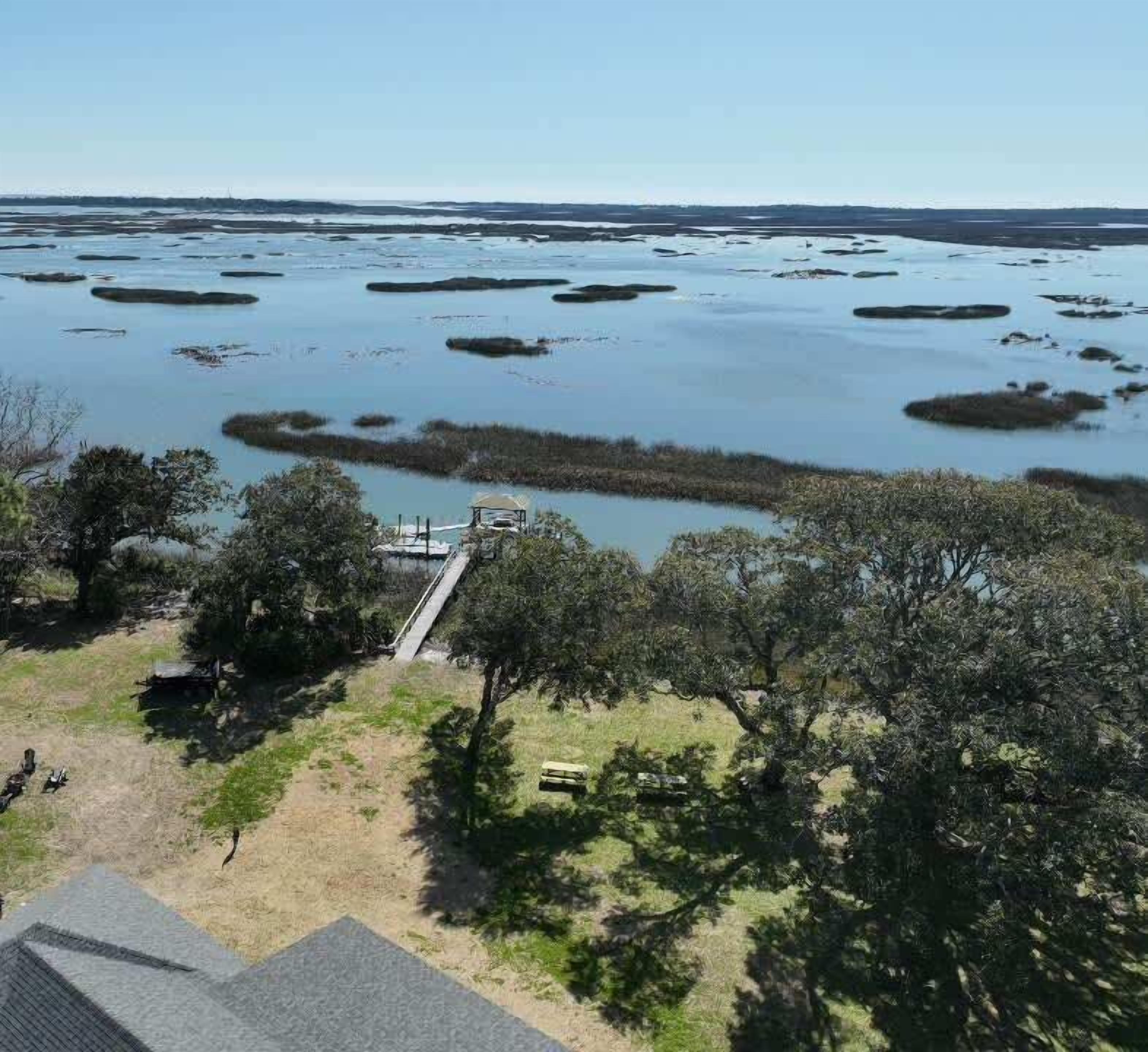 A coastal landscape with a dock extending into a calm body of water surrounded by trees.