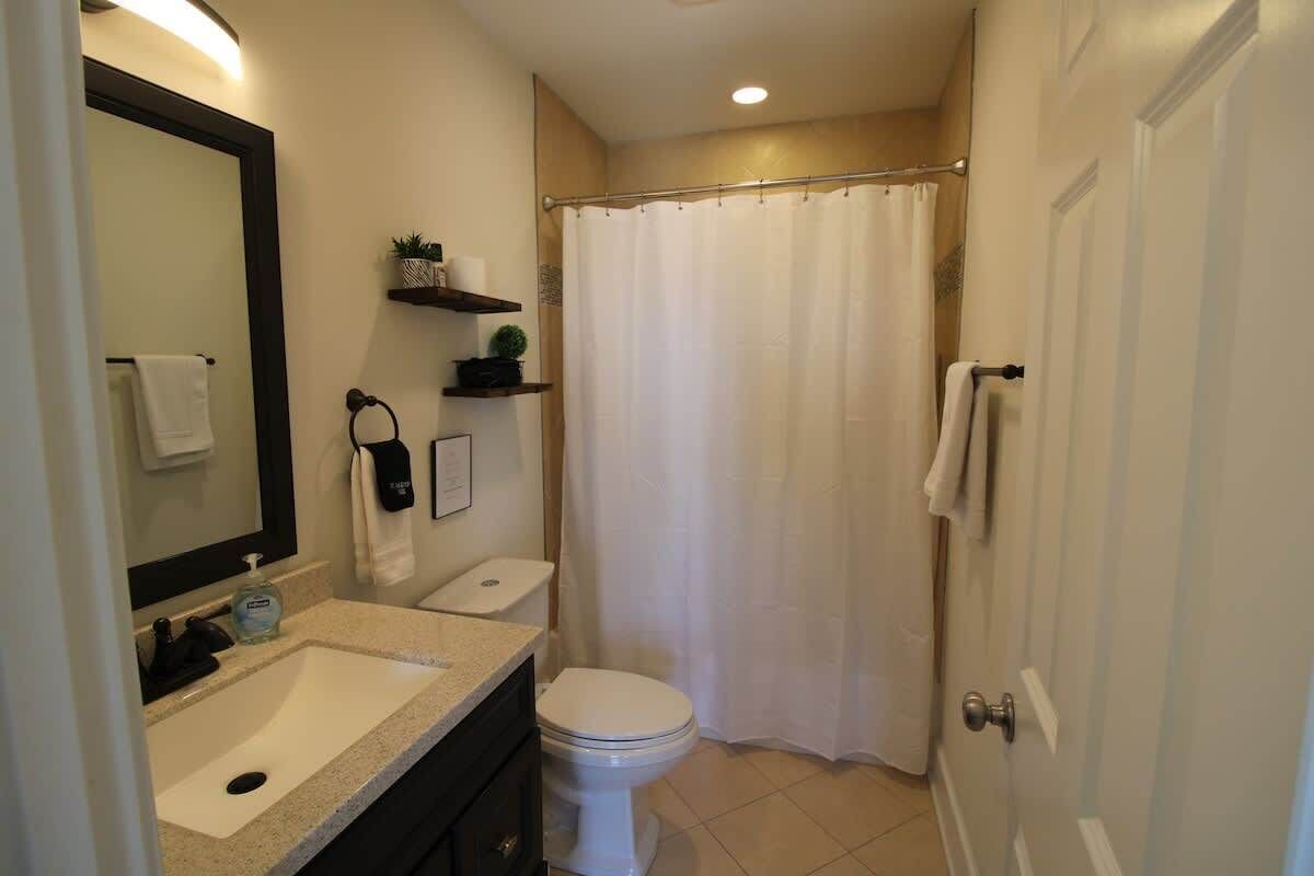 Un baño con lavamanos, inodoro y cortina de ducha.