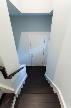 A narrow staircase with dark wooden steps and white railings, leading to a white door at the top. - Designer Apt in Charming Fort Mill w/ Netflix (Fort Mill)