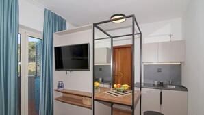 Een kleine keuken met een televisie, een houten aanrecht en een klein krukje.