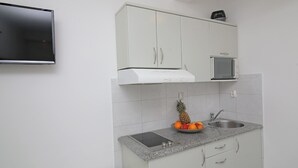 A compact kitchen with a built-in microwave, a small sink, and a granite countertop.