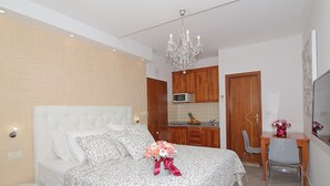 Une chambre avec un lit, un bureau, une chaise, un four à micro-ondes et une porte en bois.