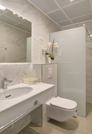 Et moderne badeværelse med vask, toilet og brusebad i marmor.