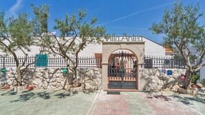 A building entrance with a stone wall, a metal gate, and trees.