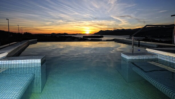 A swimming pool with a sunset view, surrounded by tiled steps and railings.