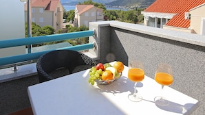 Ein Balkon mit Tisch für zwei Personen, mit Obstschale und zwei Gläsern Orangensaft.