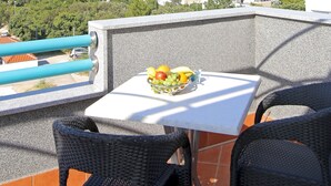 Eine Terrasse mit Tisch und Stühlen, Blick auf eine Brücke und eine gebirgige Landschaft.