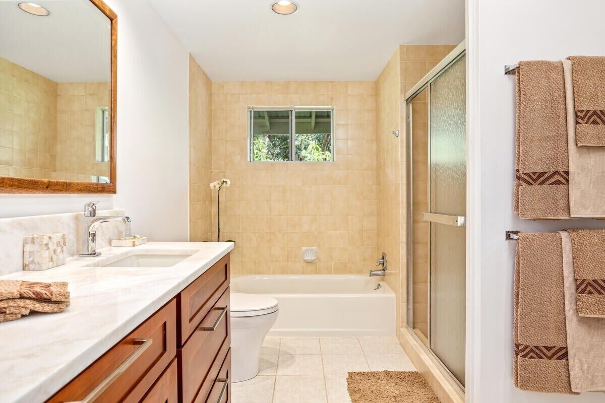 A bathroom with a large mirror, two sinks, a toilet, a bathtub, and a shower.