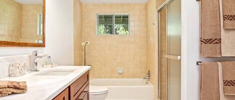 A bathroom with a large mirror, two sinks, a toilet, a bathtub, and a shower.