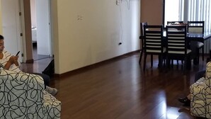 Een ruime woonkamer met een houten vloer, een eettafel met stoelen en een bank.